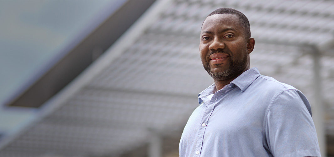Photo de Kofi, debout, dehors et souriant à l’appareil photo.
