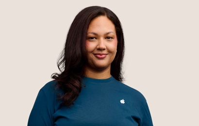 人像相片，相中的 Apple Retail 團隊成員留有深色長髮，面帶微笑。