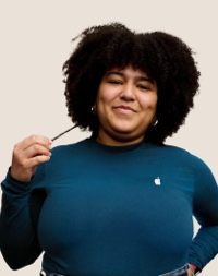 人像相片，相中的 Apple Retail 團隊成員留有深色長曲髮，面帶微笑。