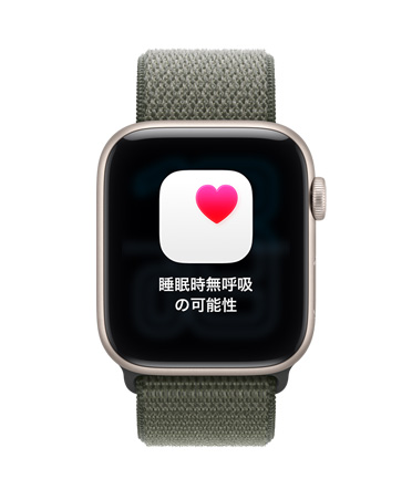 スターライトアルミニウムケースのApple Watch SE 3。睡眠時無呼吸の可能性を知らせる通知と、ピンクのハートマークが入った白いボックスが表示されている。右側面の外観にはDigital Crownがあり、フォレストのスポーツループが付いている