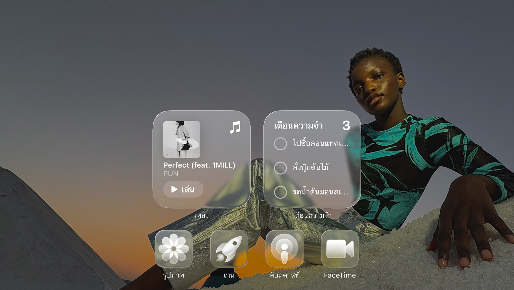 จอภาพแบบ Liquid Glass พร้อมไอคอนแอปแบบใส เช่น Apple Music, เตือนความจำ, รูปภาพ, เกม, พ็อดคาสท์ และ FaceTime ที่หักเหกับภาพพื้นหลัง