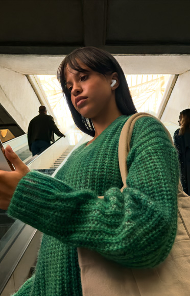 Pessoa com AirPods Pro 3 olha para o iPhone