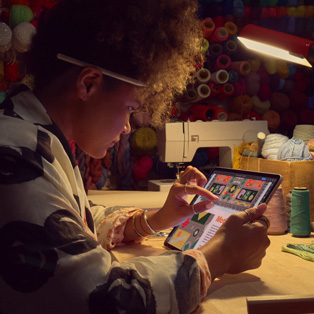 Una persona seduta alla scrivania che usa due dita sullo schermo di un iPad per ingrandire un’immagine.