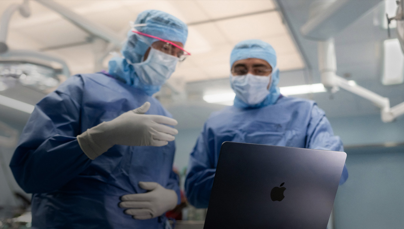Two surgeons discussing something on the screen of a MacBook Pro in the OR.