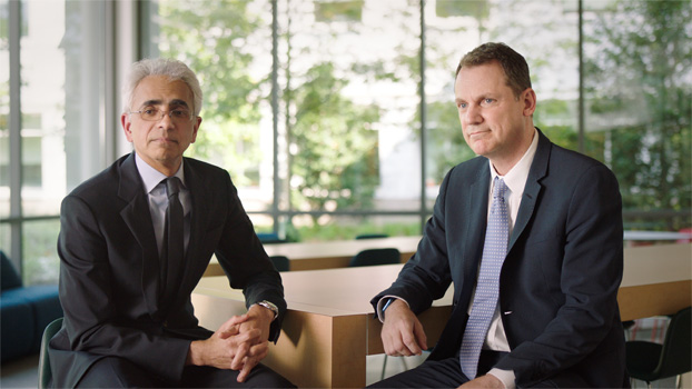 Deux personnes en costume assises à une table.