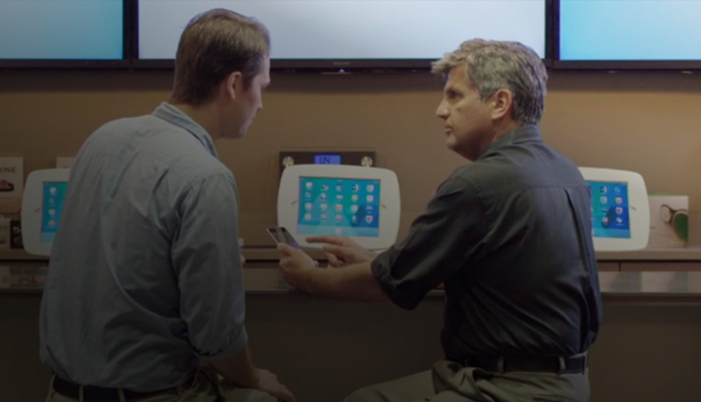 Deux hommes installés au O Bar regardent l’écran d’un iPhone.