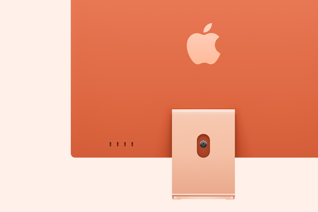 Skats no aizmugures uz oranžu iMac, izcelti četri USB‑C porti