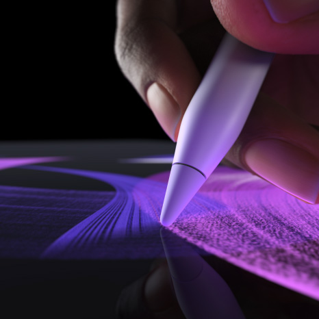 Apple Pencil Pro, sānskats, balta krāsa, roka ar zīmuli novelk koši zilu otas līniju