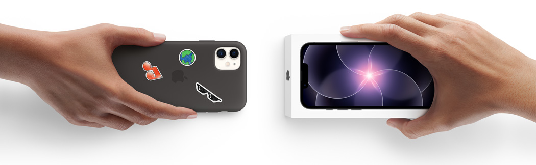 Hình ảnh hai bàn tay cạnh nhau, một bàn tay đang cầm iPhone 11 đeo ốp lưng silicon với các nhãn dán ở vỏ ngoài mặt sau, thực hiện trao đổi với một bàn tay đang cầm hộp iPhone 17e mới