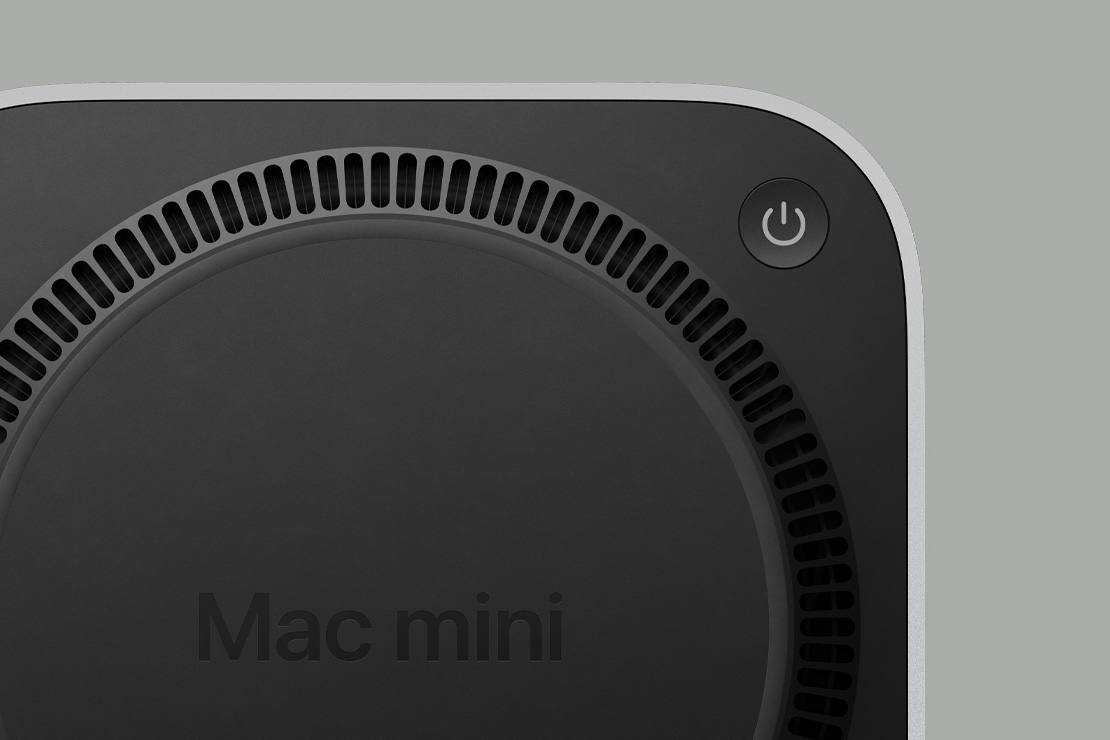 Melna Mac mini apakšdaļa ar ieslēgšanas/izslēgšanas pogu un cirkulāru, ventilatoram līdzīgu dzesēšanas sistēmu
